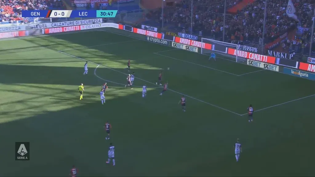 Live football feed with a hard shadow line across the pitch and sunlit advertising boards washed out by glare